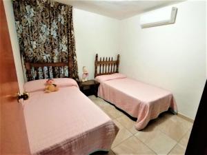 2 camas en una habitación con sábanas rosas y un osito de peluche en Depa Centrico Mazatlan a 2 cuadras de a Playa, Central, Acuario., en Mazatlán