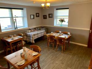 a restaurant with wooden tables and chairs and windows at The Fife Arms Hotel in Keith