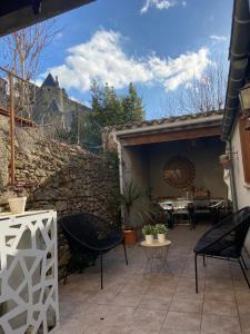 a patio with chairs and a table and a stone wall at Côte de la Cité in Carcassonne