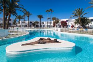 a swimming pool at a resort with palm trees at Los Barqueros 8 by Best Holidays Fuerteventura in Corralejo