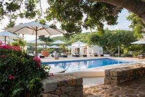 una piscina con sillas y sombrillas en Hotel Rural & Spa Can Curreu, en Sant Carles de Peralta