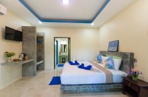 a bedroom with a large white bed with blue pillows at The Sun Long Beach Resort in Ko Lanta