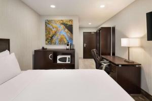 a hotel room with a bed and a desk and a microwave at Days Inn by Wyndham Wainwright in Wainwright