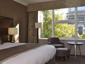 um quarto com uma cama, uma cadeira e uma janela em Mercure Winchester Wessex Hotel em Winchester