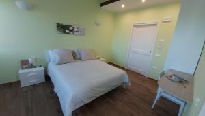 a small bedroom with a white bed and a door at Lumacanda in Mombaroccio