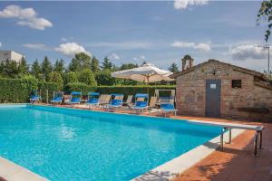 a swimming pool with chairs and an umbrella at L'Oasi della Pergola in Castiglione del Lago