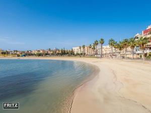 a beach with palm trees and buildings and the water at Reno's Guest House in Birżebbuġa