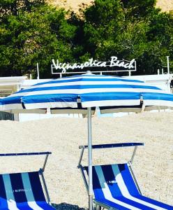 two blue and white umbrellas and chairs on a beach at Camping Apartment Vignanotica in Mattinata