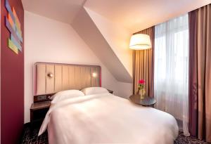 a bedroom with a large white bed and a window at Park Inn by Radisson Nürnberg in Nuremberg +102 photos