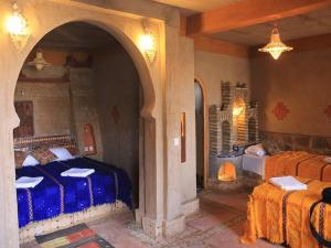 1 dormitorio con 2 camas y puerta abovedada en Kasbah Azalay Merzouga en Merzouga