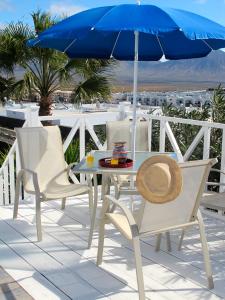 a table and chairs with a blue umbrella at VILLA DE LA VISTA in Playa Blanca