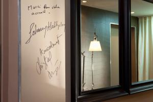 un miroir avec écriture sur le mur à côté d'une lampe dans l'établissement Hotel Du Golf, à Saint-Étienne