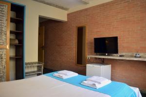 a bedroom with a bed with a tv on a brick wall at Ilha Deck Hotel in Ilhabela