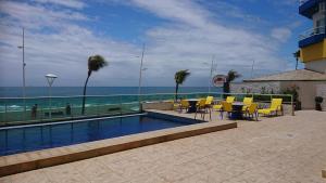 a swimming pool with yellow chairs and a view of the ocean at FLAT O POINT do CARNAVAL do FAROL da BARRA in Salvador