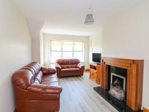 uma sala de estar com um sofá de couro e uma lareira em Doornogue em Fethard on Sea