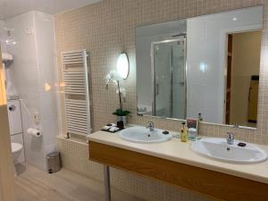 a bathroom with two sinks and a large mirror at Bayview Hotel in Bushmills