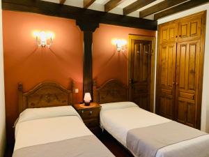 a bedroom with two beds and two lights on the wall at La Posada de Abanillas in Abanillas