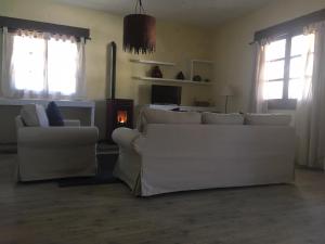 sala de estar con sofás blancos y chimenea en La Cobacha, en Cazalla de la Sierra