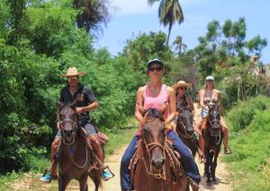 a group of people riding horses down a dirt road at Selina Puerto Escondido in Puerto Escondido