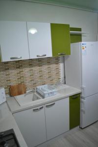 Una cocina con gabinetes blancos y un refrigerador blanco. en Green rooms Hunedoara, en Hunedoara