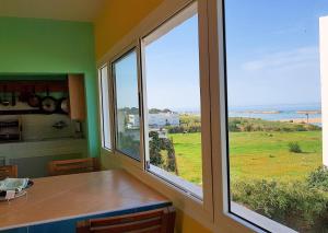 a kitchen with two windows and a view of the ocean at Maison de la Lagune in Oualidia