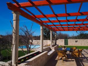 um pátio com uma mesa e cadeiras sob uma pérgola em Villa Antonija em Čilipi