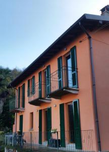 pomarańczowy budynek z zielonymi okiennicami i balkonami w obiekcie B&B Val Valerna w mieście Lezzeno