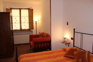 a bedroom with a bed and a chair and a window at Agriturismo Fonteverdi in Boccheggiano
