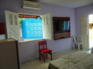 1 dormitorio con cama, silla roja y ventana en Pousada Don Robledo, en São Miguel dos Milagres