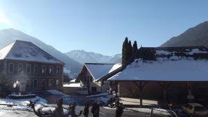een met sneeuw bedekt dorp met een gebouw en bergen bij Les Tilleuls in Le Biot