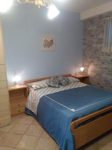 - une chambre avec un lit avec des draps bleus et deux lampes dans l'établissement Ai tre archi, à Mascali