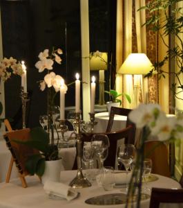 una mesa con velas y flores encima en L'Hôtel Le Cheval Noir, en Moret-sur-Loing