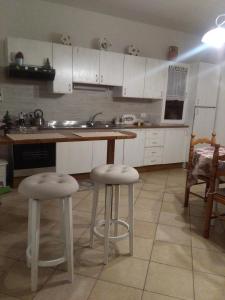 a kitchen with white cabinets and bar stools at Ai tre archi in Mascali