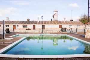 an empty pool in front of a building with a lighthouse at Casas rurales Puente Romano in Sonseca