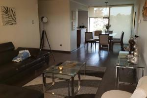 ein Wohnzimmer mit einem Sofa und einem Tisch in der Unterkunft Espectacular Departamento Marina Golf Rapel in Las Cabras