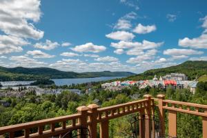 a view of a town and a lake from a wooden railing at L'Altitude by Rendez-Vous Mont-Tremblant in Mont-Tremblant