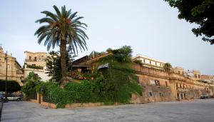 a building with a palm tree on a street at Cleopatra B&B in Palermo