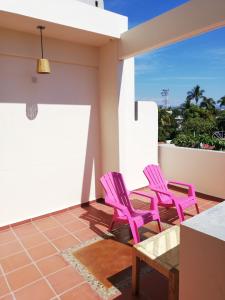 a pair of pink chairs on the balcony of a house at Casa Puerto Bonito & Private Coworking in Puerto Escondido