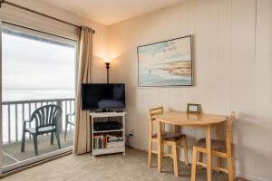 een woonkamer met een tafel, een televisie en een raam bij Pacific Sands Resort in Neskowin