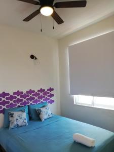 a bedroom with a blue bed with a ceiling fan at Casa Puerto Bonito & Private Coworking in Puerto Escondido