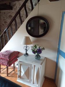 a table with a lamp and a chair and a mirror at Gîte Moulin de Ludièras in Busserolles