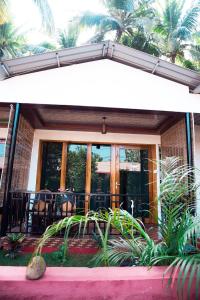 ein Haus mit einer Veranda mit Glastüren und Pflanzen in der Unterkunft Patnem Beach Cottages in Patnem