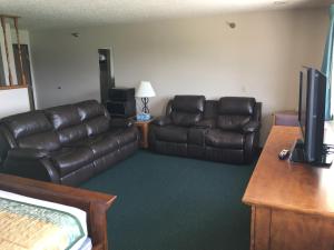 a living room with two leather couches and a television at Cassville Four Seasons Inn & Suites in Cassville