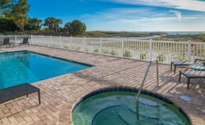 a swimming pool on a brick patio with a white fence at Provident Oceana Beachfront Suites in St. Pete Beach