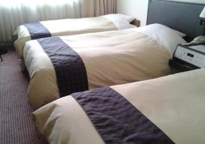 three beds in a hotel room with white and blue blankets at Ogaki Forum Hotel / Vacation STAY 72183 in Ogaki