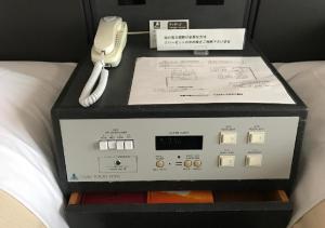 a phone sitting on top of a box on a bed at Ogaki Forum Hotel / Vacation STAY 72179 in Ogaki +8 photos