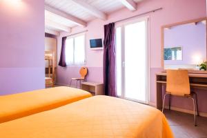 a bedroom with two beds and a desk and a window at Hotel Mary Fleur in Rimini