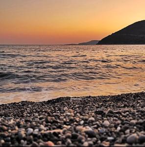 a rocky beach with the sun setting over the water at Sempati Apart in Mesudiye