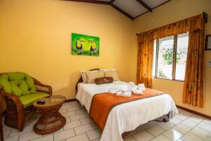 een slaapkamer met een bed, een stoel en een raam bij Hotel La Rosa de America in Alajuela