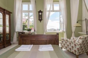 a bedroom with a bed and a chair and windows at Villa Maria-Syros in Ermoupoli